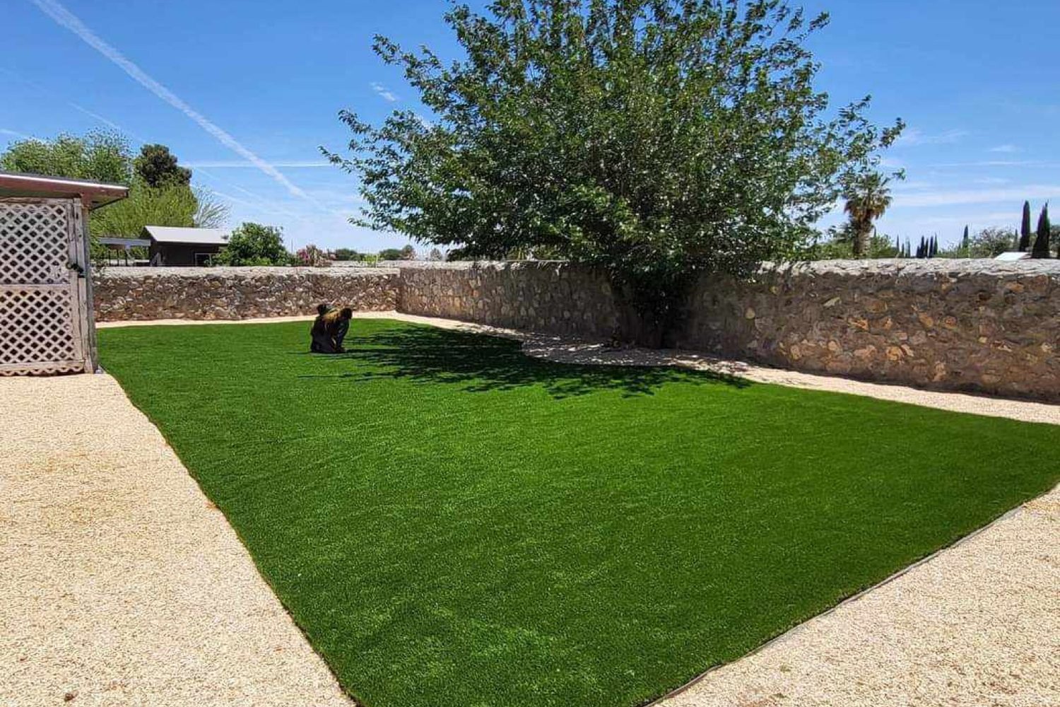 Large artificial turf yard bordered by a stone wall