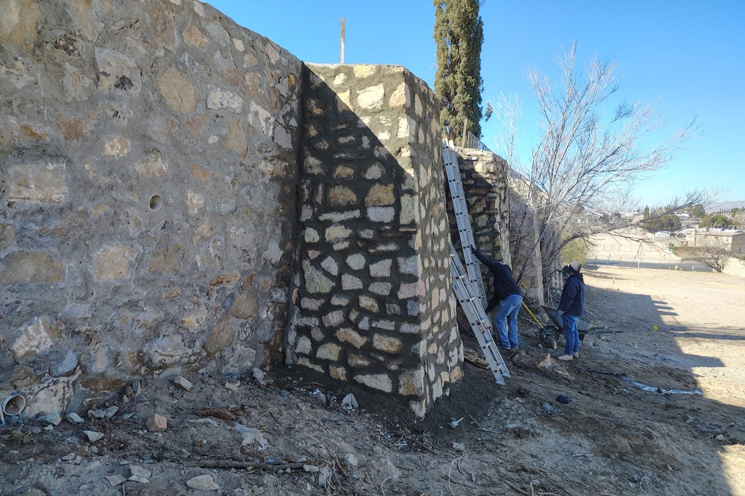 Tall rock wall corner going up along a property line
