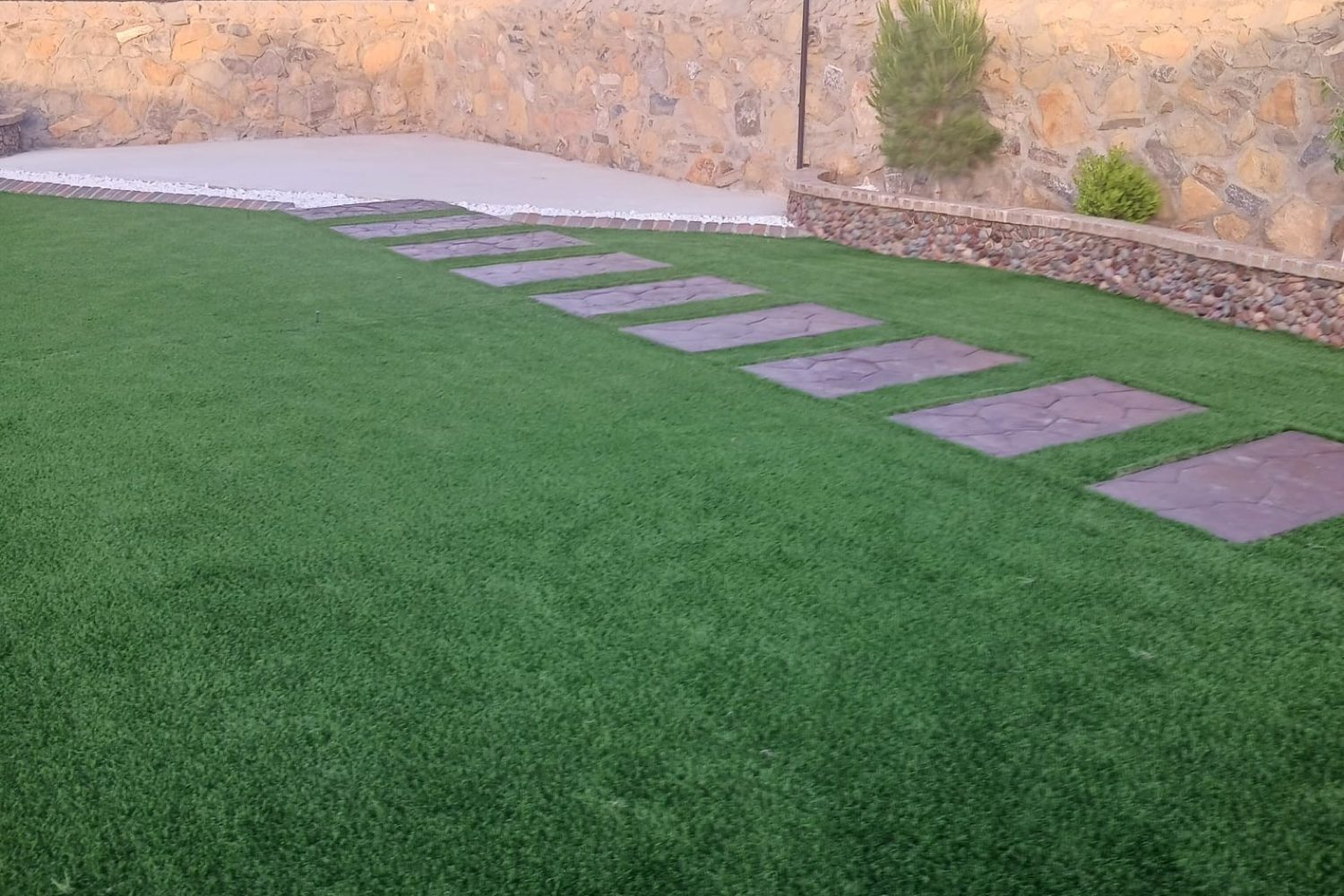 Turf yard with stepping stones and a stone border